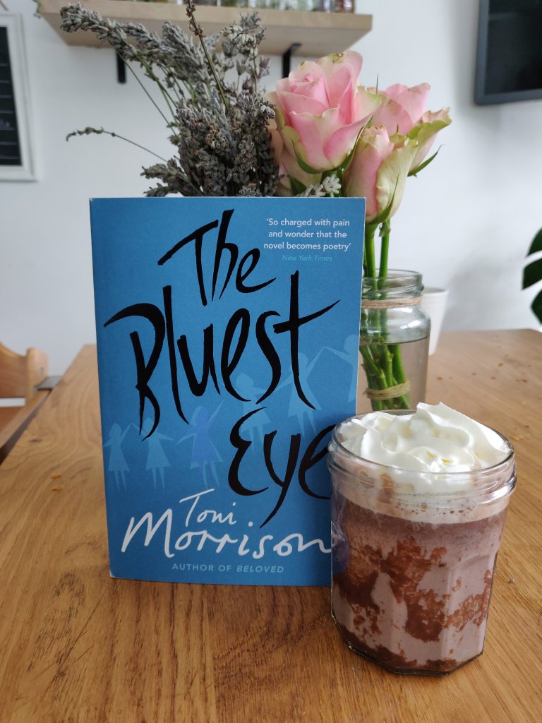 Image of the book, The Bluest Eye and a cup of hot chocolate